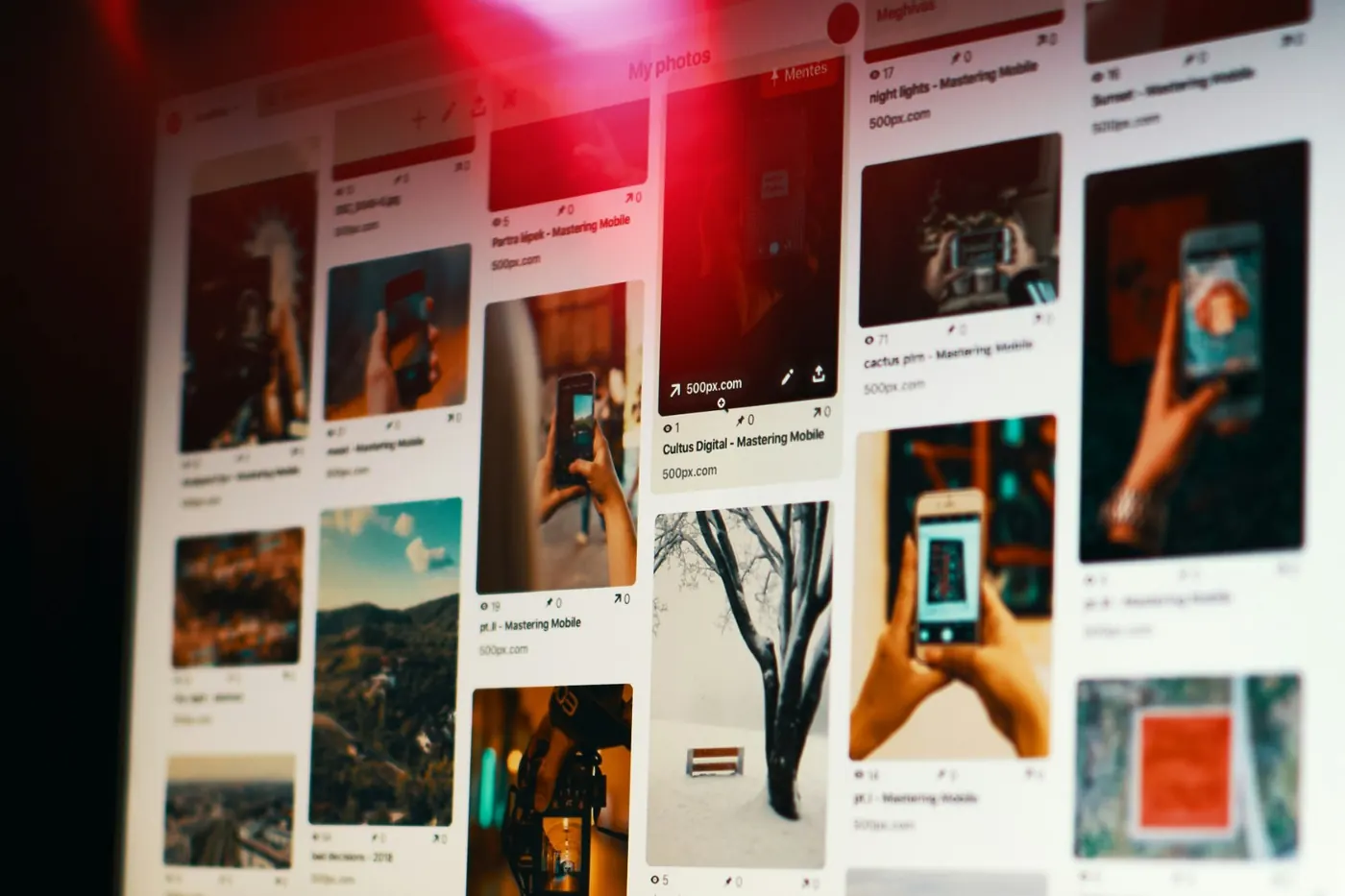 A laptop showing a grid of photos in a dark room lit with red light
