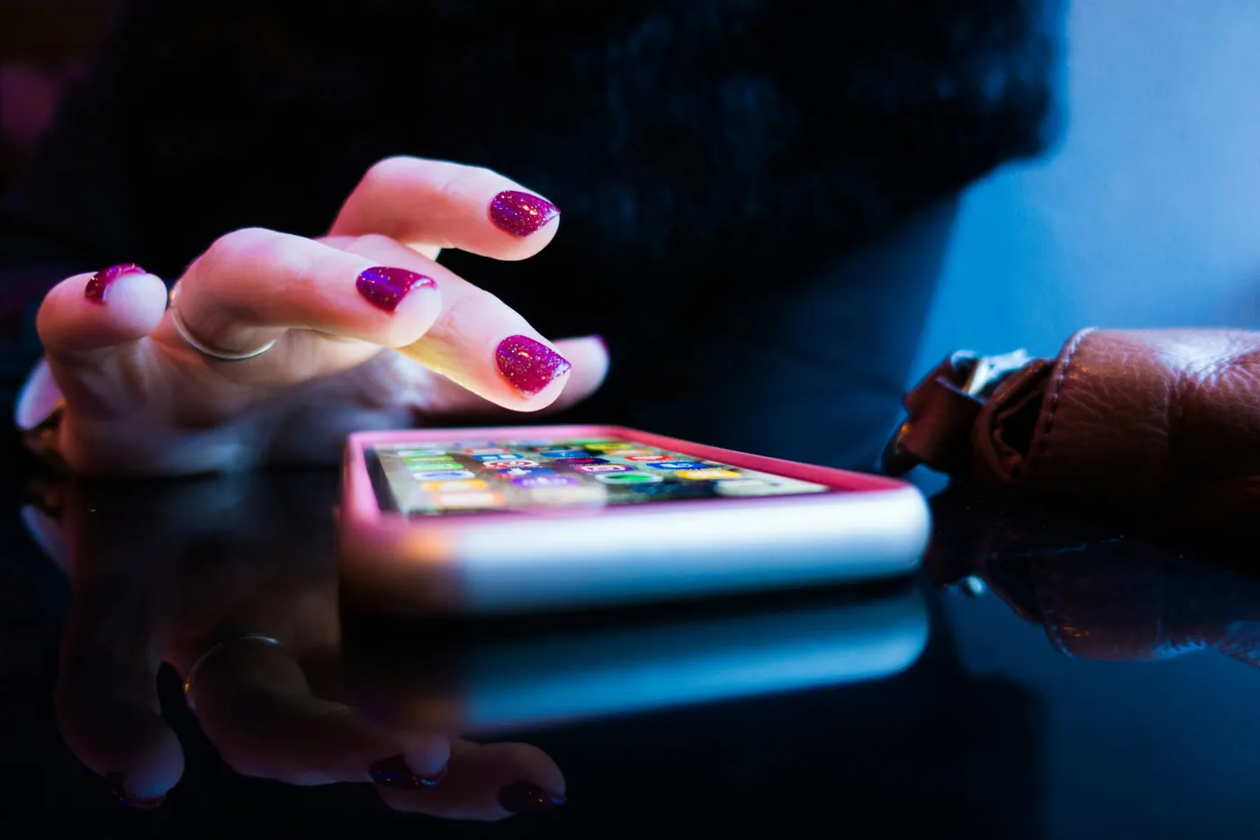 A hand tapping a phone screen full of apps