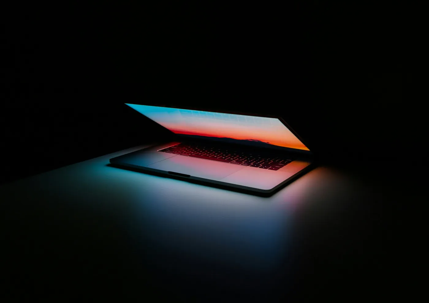 A laptop opening in the dark with a glowing screen